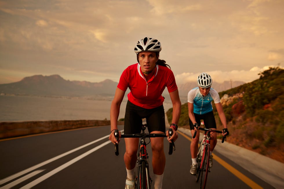 professional female cyclists on road bikes at sunset