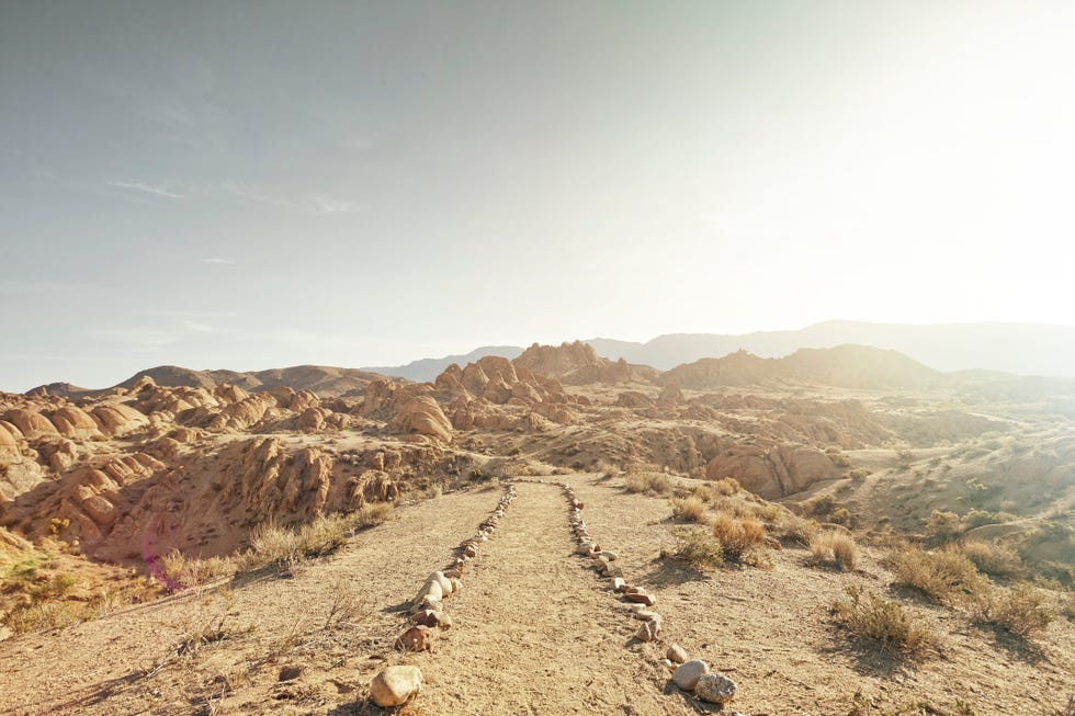 a dirt path leading to a rocky landscape at sunrise in alabama hills, ca
