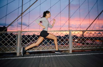 woman running on a bridge at sunset