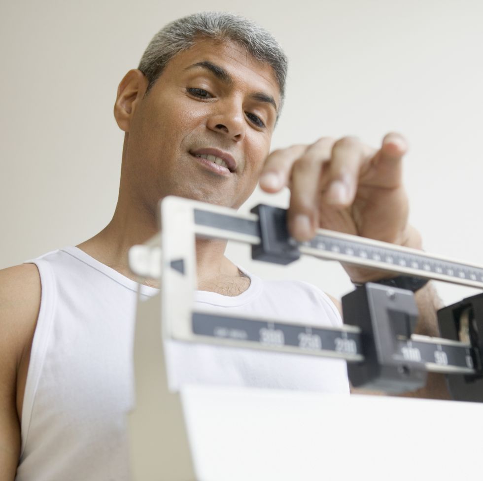 Middle aged man weighing himself
