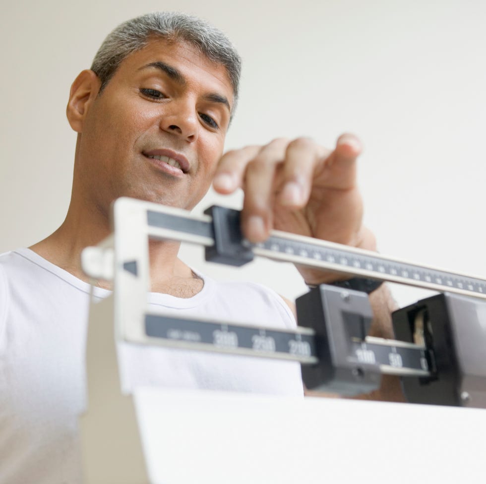 Middle aged man weighing himself