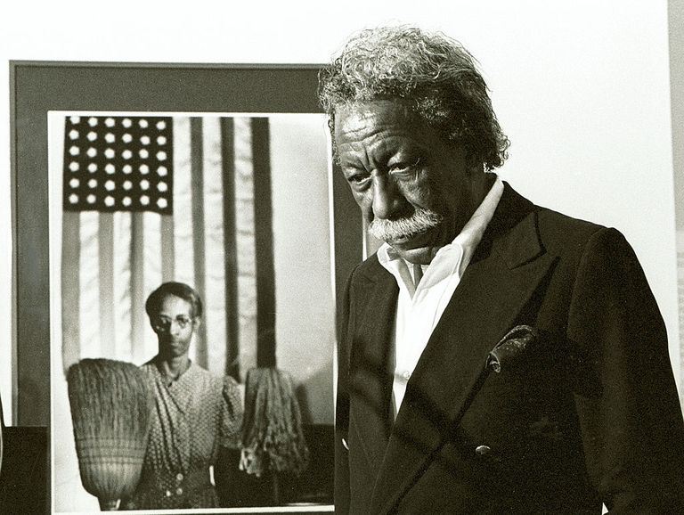 american photographer and film director gordon parks 1912   2006 stands next to one of his most famous images, american gothic, which depicts a cleaning woman who holds a mop and broom beneath a large american flag, norton museum of art, west palm beach, florida, 1984 parks was best known for his work in black america and the problems with poverty but also wrote fiction, journalism, and music, and was a choreographer and jazz performer photo by john pinedagetty images