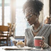 Woman using cell phone at breakfast in cafe
