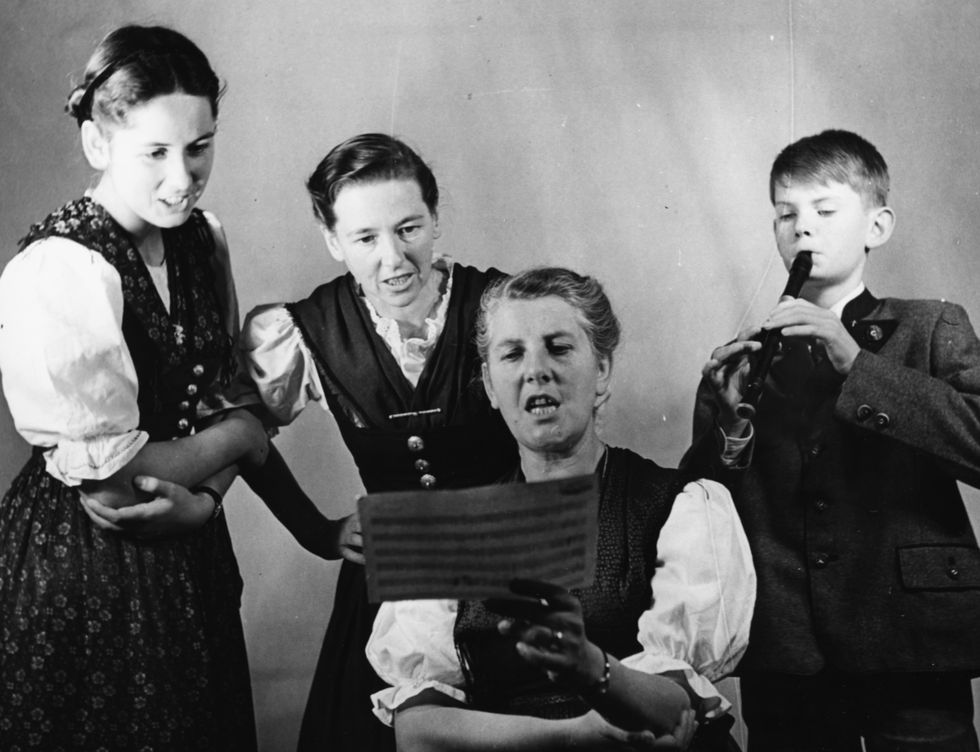Maria Von Trapp and three of her children, (L-R) Eleonore, Agatha and Johannes, singing from a piece of sheet music, London, circa 1950.