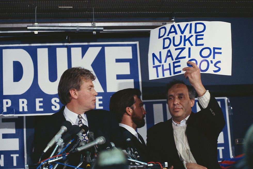 a protester holds up a sign reading, david duke nazi of the 90s, interrupting david dukes speech during a campaign rally photo by © wally mcnameecorbiscorbis via getty images