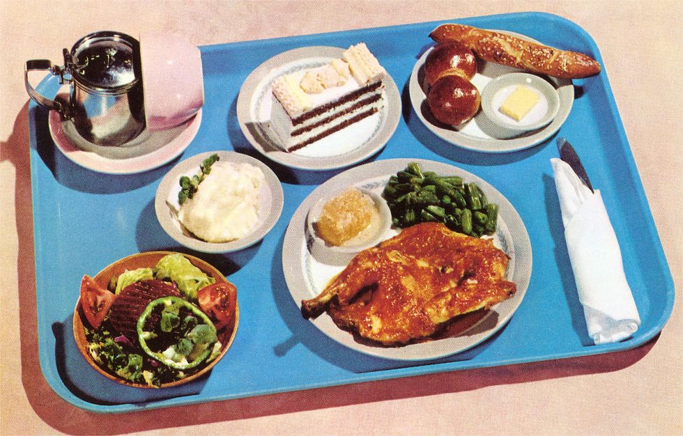 vintage color photograph of of a blue plastic tray holding a complete dinner on five different plates including a main course, rolls, salad, potatoes, dessert and a pot of tea, 1950s photo by found image holdingscorbis via getty images