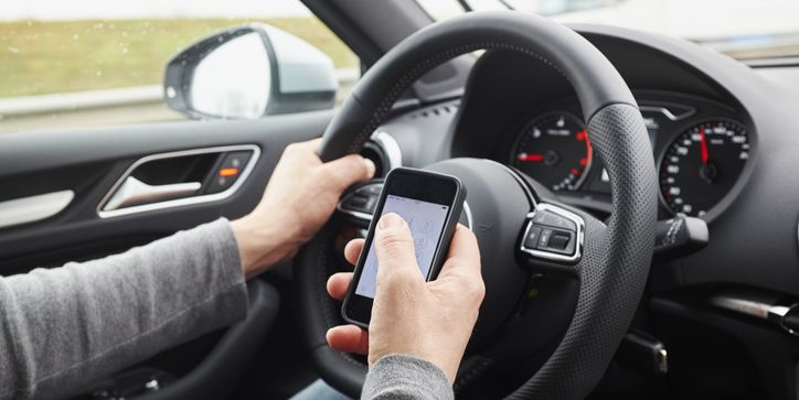 Cropped shot of man using smartphone whilst driving