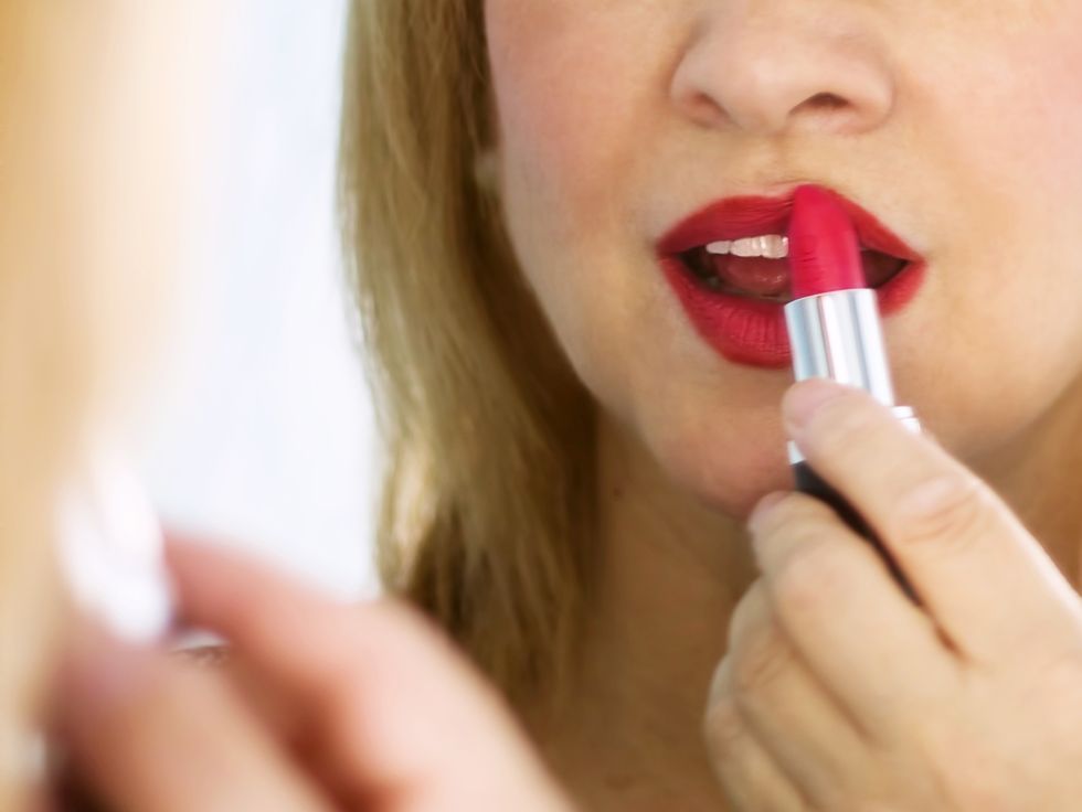 young woman puts on lipstick