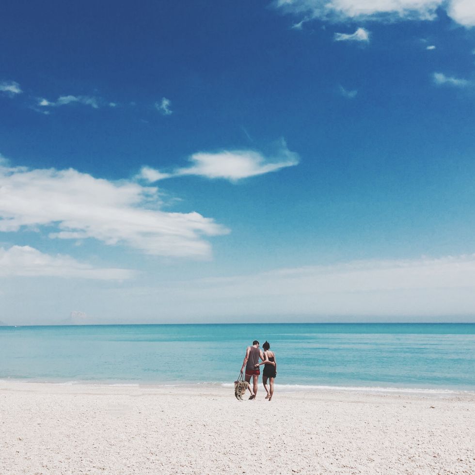 Couple Walking In Arm Around At Beach Against Sky