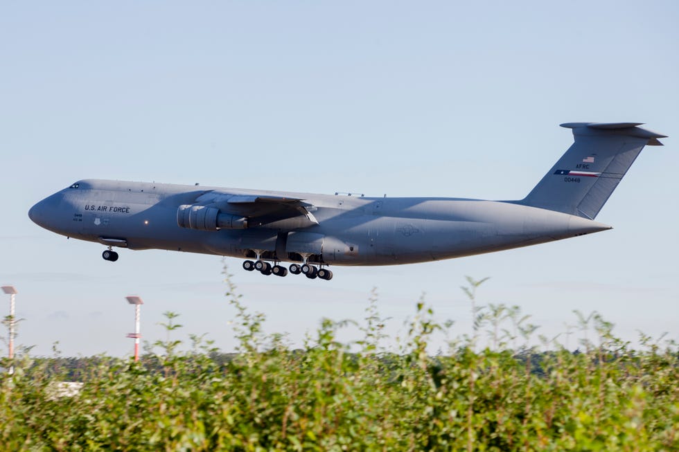 lockheed c5 galaxy taking off, with foliage in the foreground