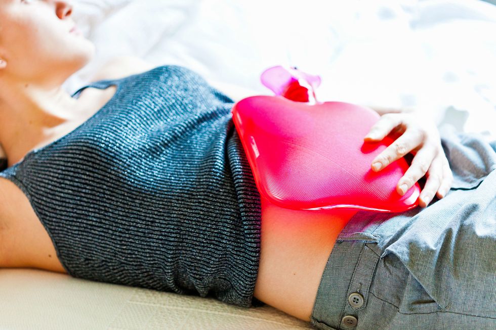 Woman using a hot-water bottle on her belly to releive abdominal pain.