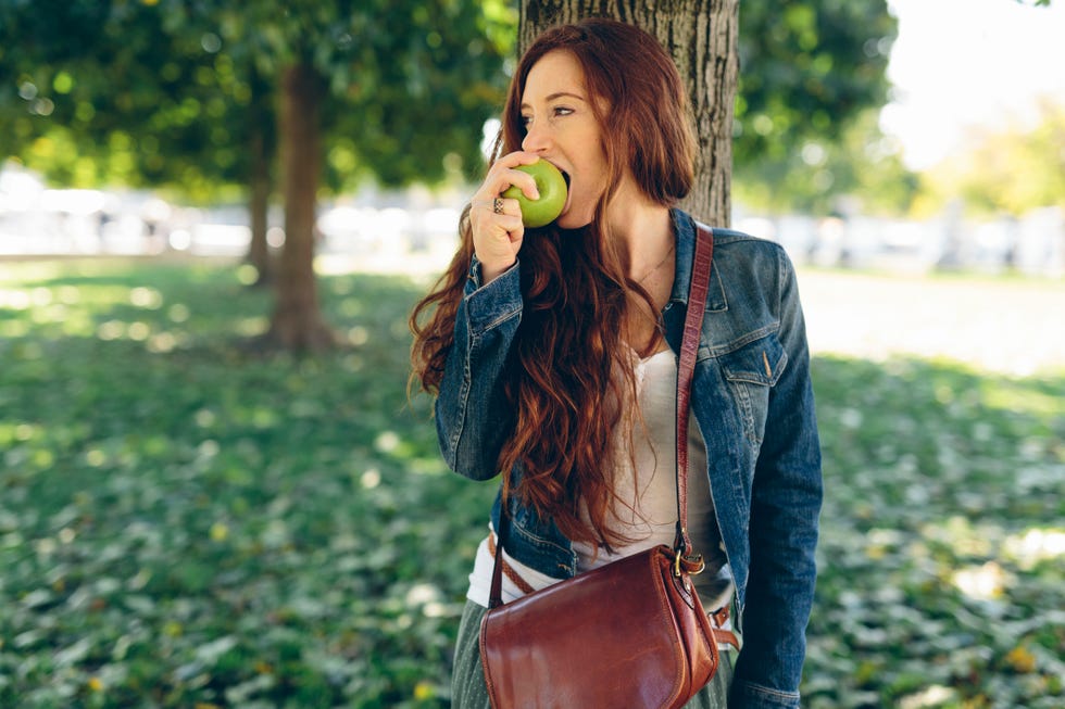 Woman eating an apple in park