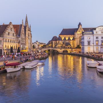 a body of water with boats in it and buildings around it with ghent in the background