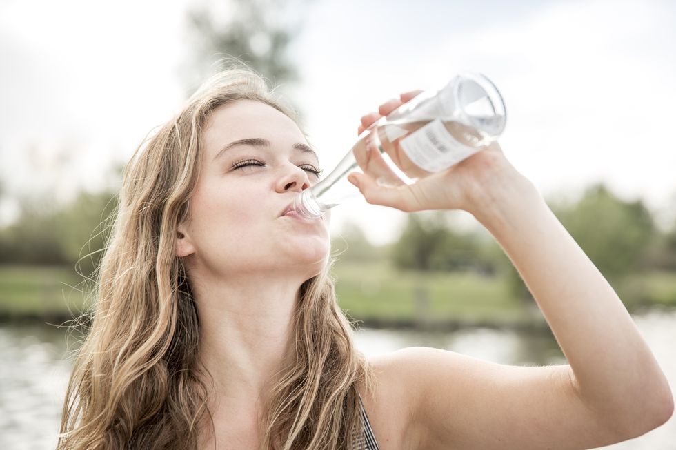 young woman drinking water from bottle, outdoors