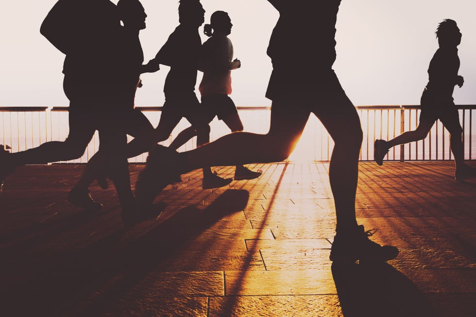people running and practicing sports on the very first light of the day during the sunrise on the barcelona shoreline boardwalk with nice silhouettes and the sun on the horizon over the mediterranean sea