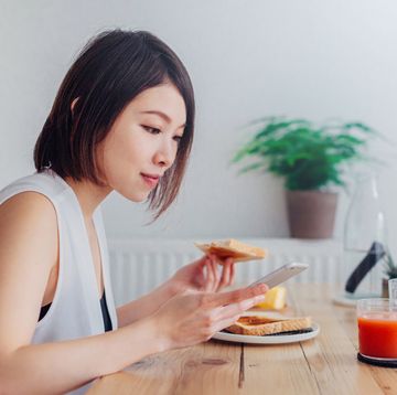Young lady using smartphone at breakfast