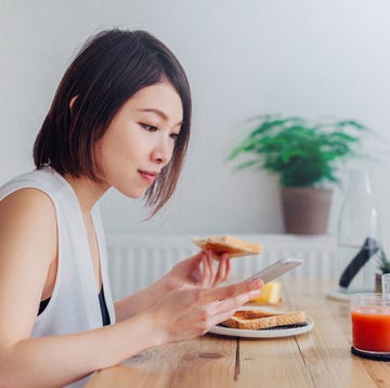 Young lady using smartphone at breakfast Young lady using smartphone at breakfast