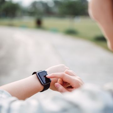 pretty young lady using a smart watch in the countryside pathway