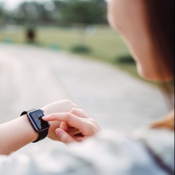pretty young lady using a smart watch in the countryside pathway