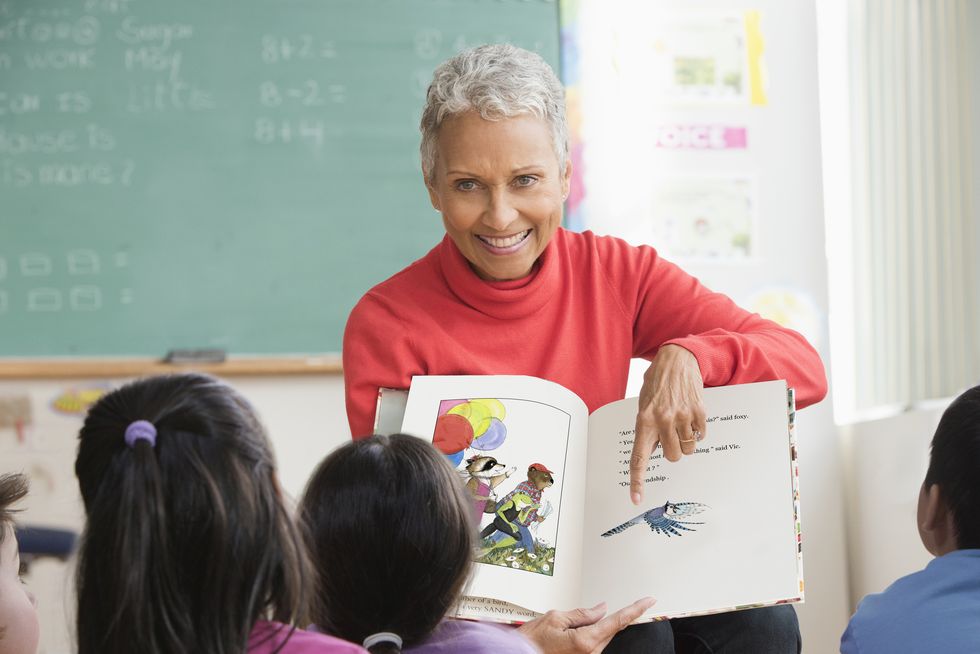 a person holding a book in front of a group of children