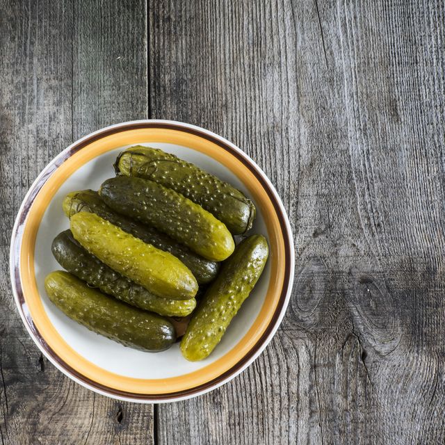 Pickled green gherkins in a bowl on a wooden table