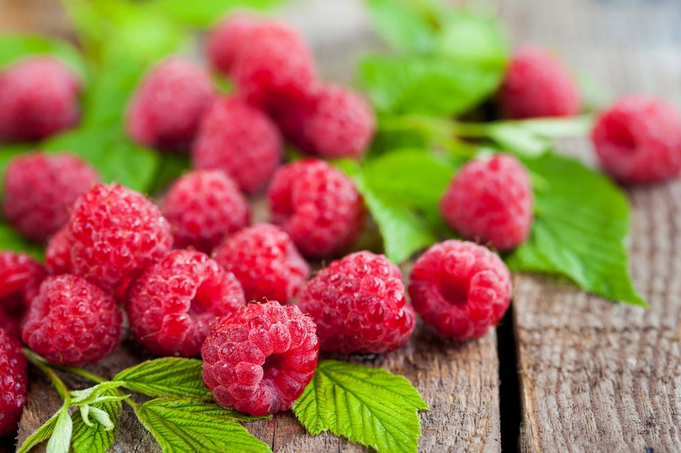 fresh organic ripe raspberry with leaves on wooden table,  selective focus