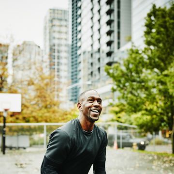 laughing basketball player preparing to shoot on outdoor basketball court in downtown neighborhood