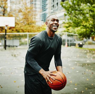 laughing basketball player preparing to shoot on outdoor basketball court in downtown neighborhood