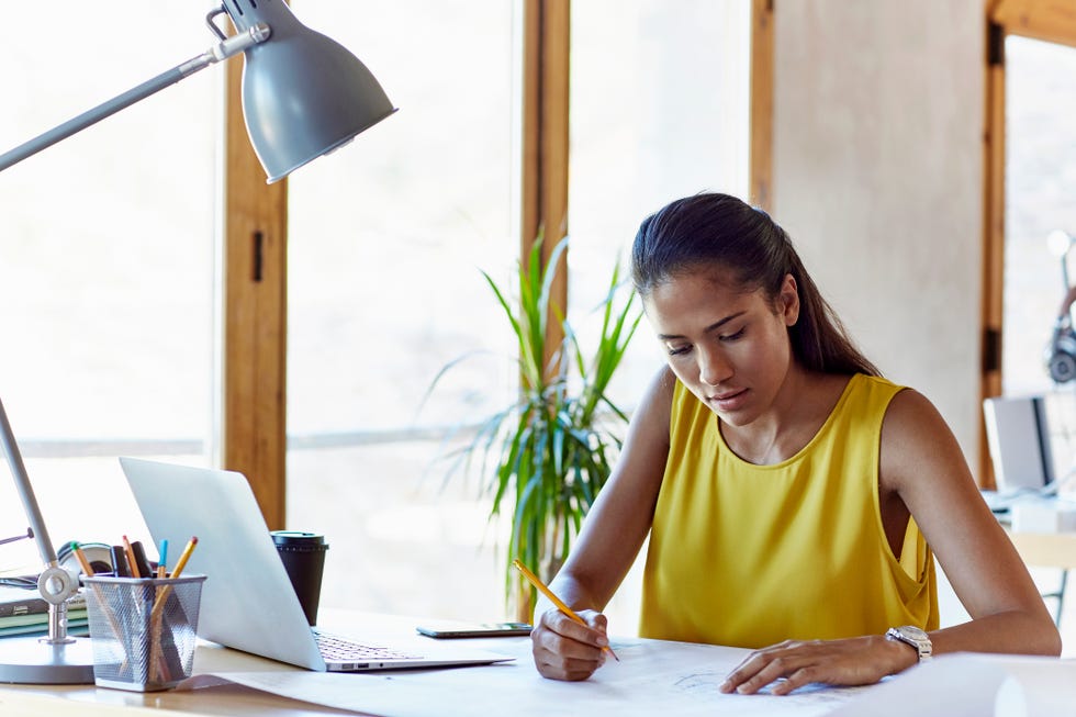 Businesswoman analyzing blueprint in office