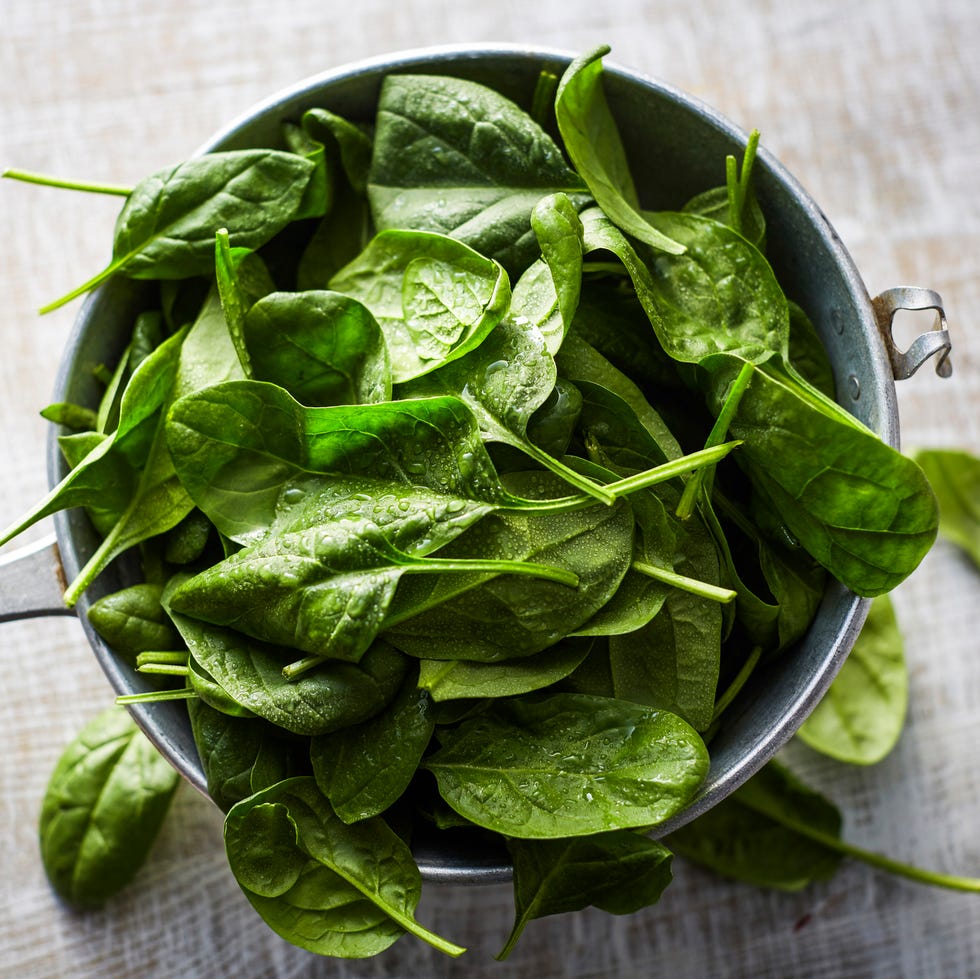 Fresh spinach leaves in colander on wood spinach natch
