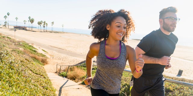 Couple running along pathway by beach