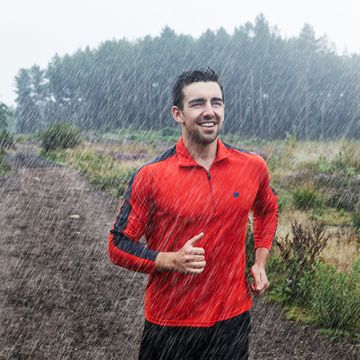 hombre corriendo bajo la lluvia con sudadera roja