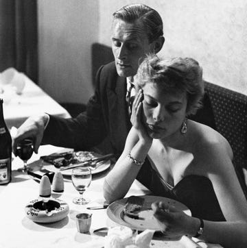 a woman and a man sitting at a table eating food