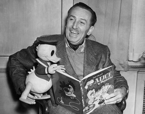 Film producer and cartoonist Walt Disney with a toy Donald Duck reading Alice in Wonderland, 1951.