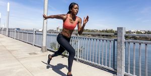 african american adult female sprinting next to a body of water in an urban environment