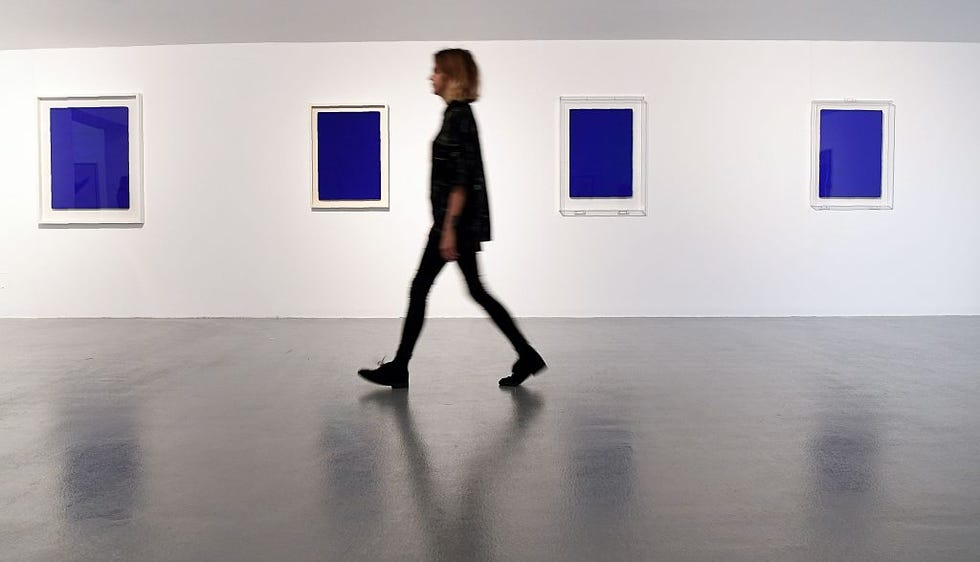 A curator walks past untitled works by French artist Yves Klein exhibited as part of the opening of the winter season at the Tate Gallery in Liverpool, North West England on October 20, 2016. AFP Paul Ellis restricted for editorial use requires mandatory credit to the artist when publishing illustrating the event listed in photo caption, should read Paul Ellishap via Getty Images