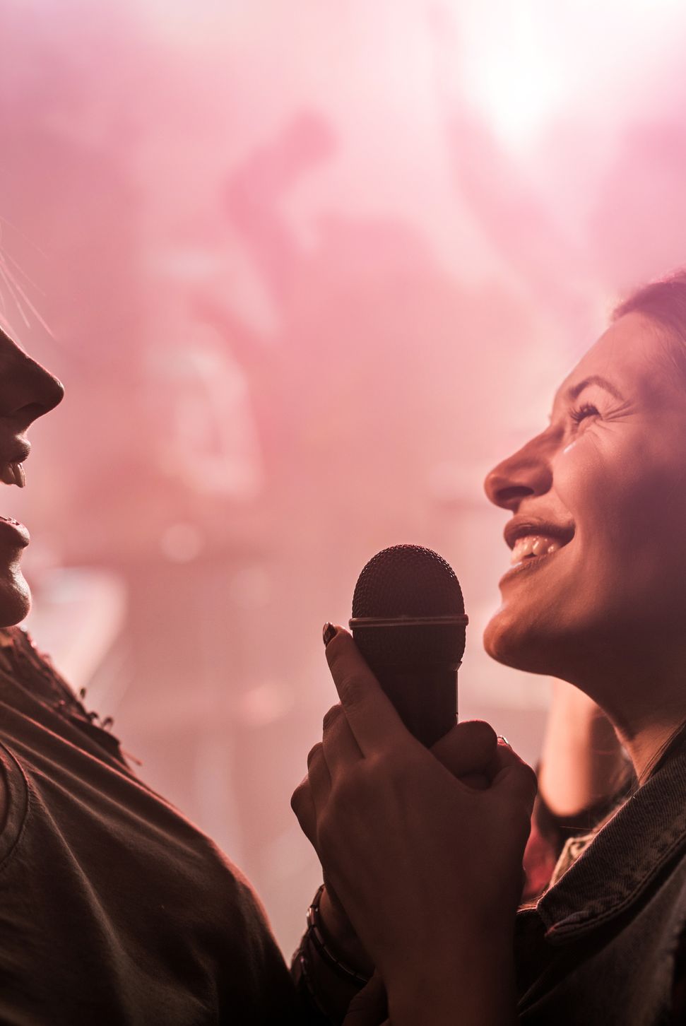Two cheerful women singing karaoke at disco club.