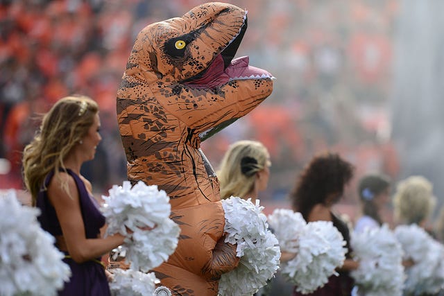 Broncos Cheerleader Dances in a T-Rex Halloween Costume