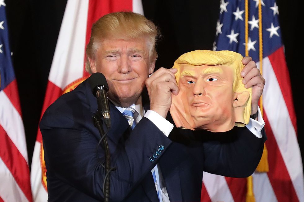Donald Trump holding mask of himself