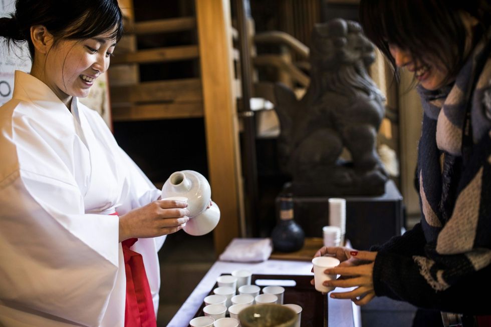 Tijdens het doburokufestival in Tokio het festival van de ongefilterde sake krijgen bezoekers aan de Koami Shintotempel wat sake in een bekertje geschonken 28 november 2016