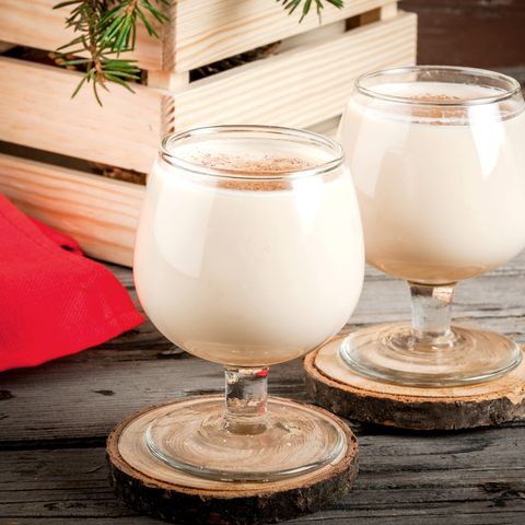 traditional christmas alcoholic cocktail   irish cream, cola de mono monkey tail, decorated with cinnamon against the background of christmas decorations on a wooden table copy space