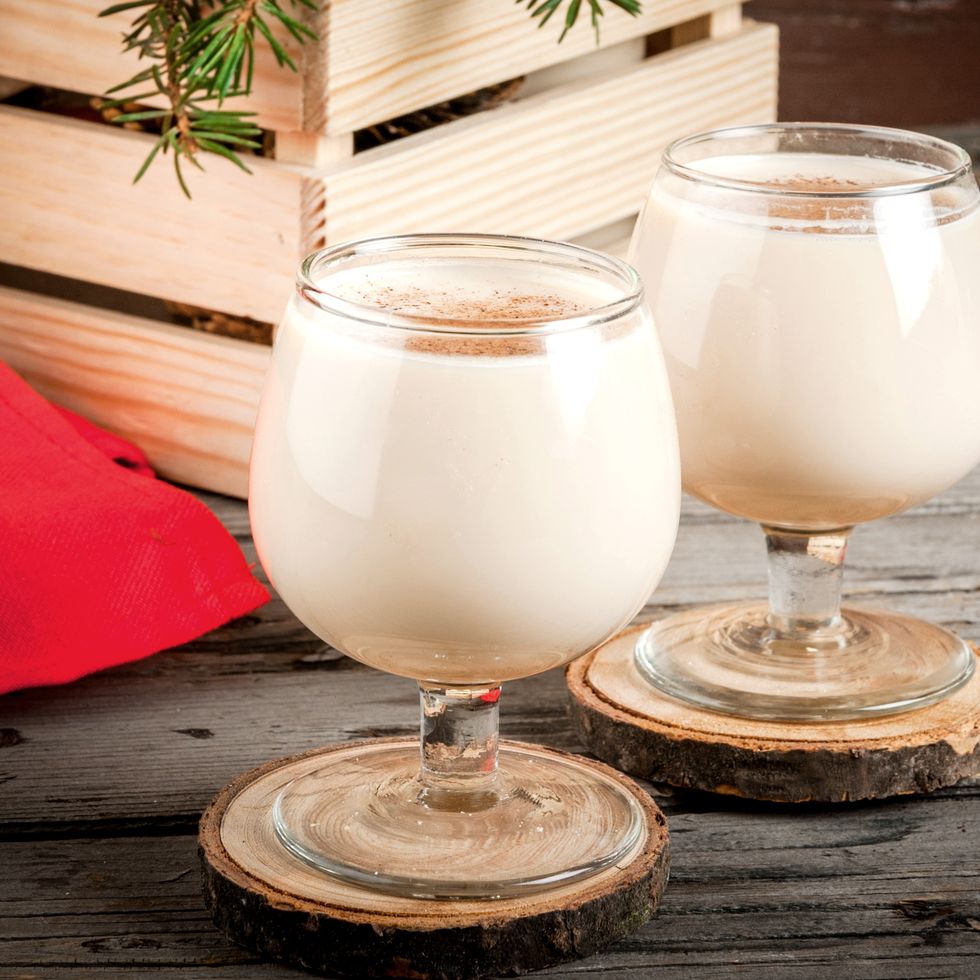 traditional christmas alcoholic cocktail   irish cream, cola de mono monkey tail, decorated with cinnamon against the background of christmas decorations on a wooden table copy space