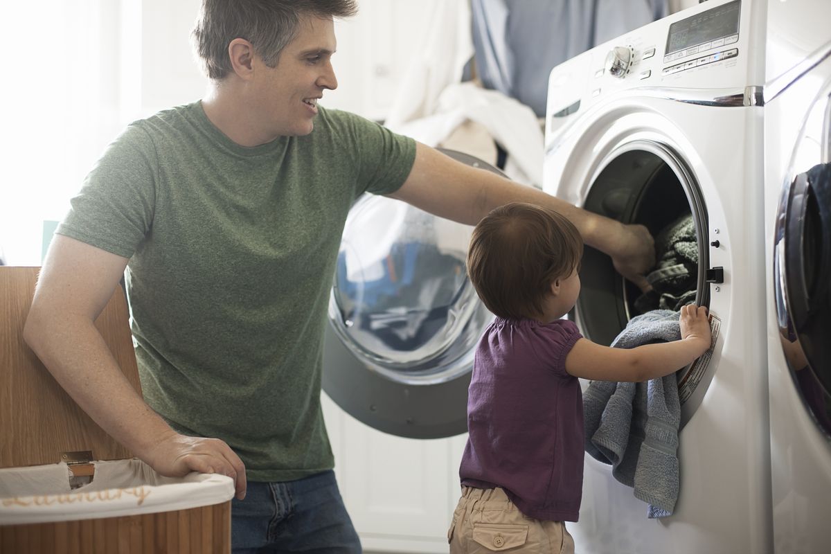 a man and a toddler emptying the laundry from the washing machine