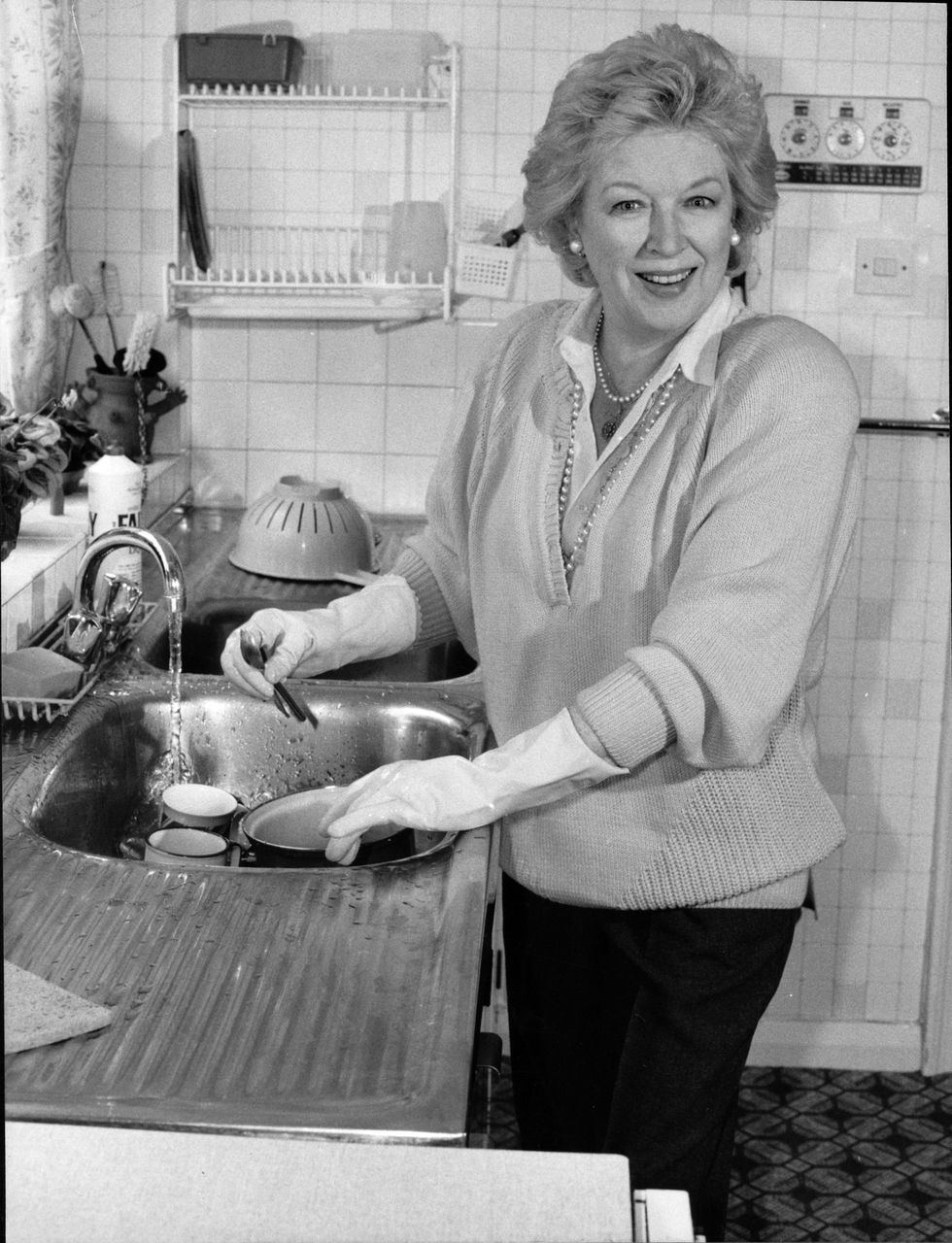 June Whitfield, TV actress, at her home in Wimbledondoing the washing up in her rubber gloves.