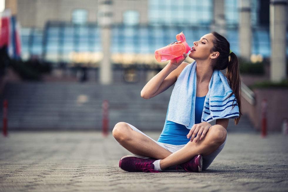 Young female athlete having a water break outdoors.