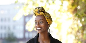 beautiful, young, happy muslim woman photographed in an bright outdoor urban setting wearing a yellow, decorated wrap around her head