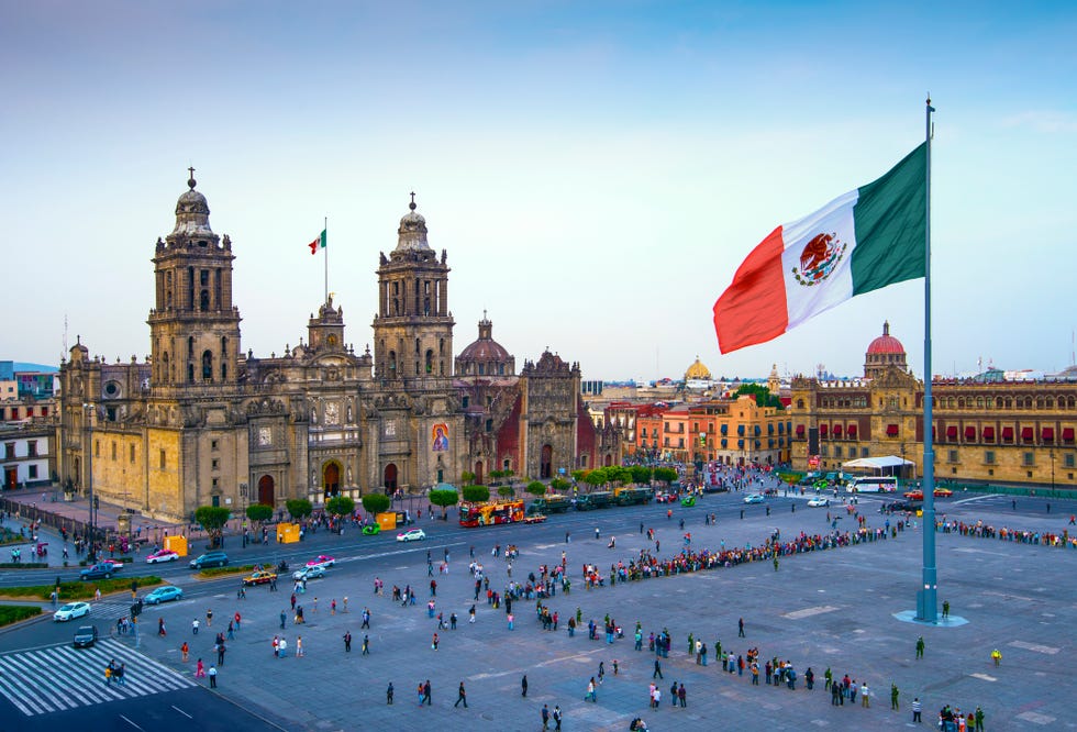 the mexican flag flies over the zocalo, the main square in mexico city the metropolitan cathedral faces the square, also referred to as constitution square