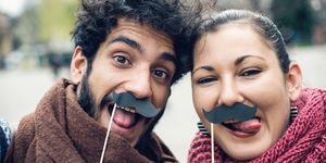couple making funny faces and making selfie with fake moustaches
