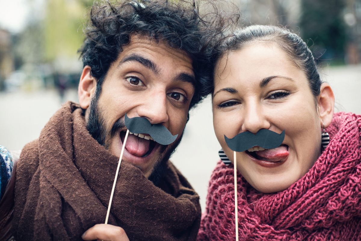 couple making funny faces and making selfie with fake moustaches