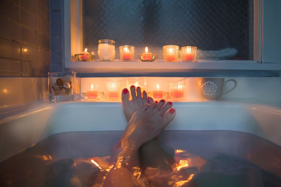 a person in a bathtub with candles in it